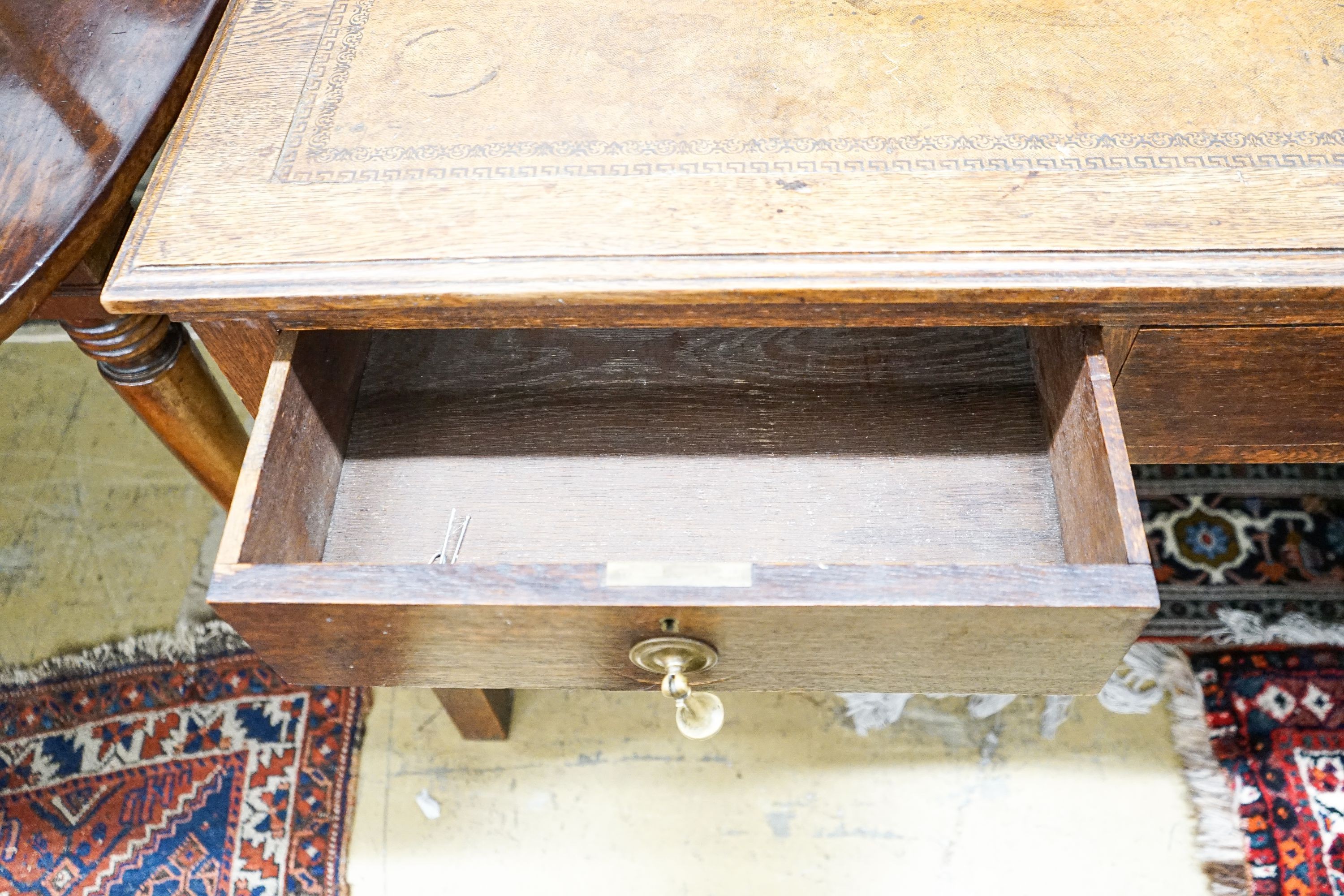 A 1920's oak two drawer writing table, with a leather inset top, length 106cm, depth 52cm, height 75cm